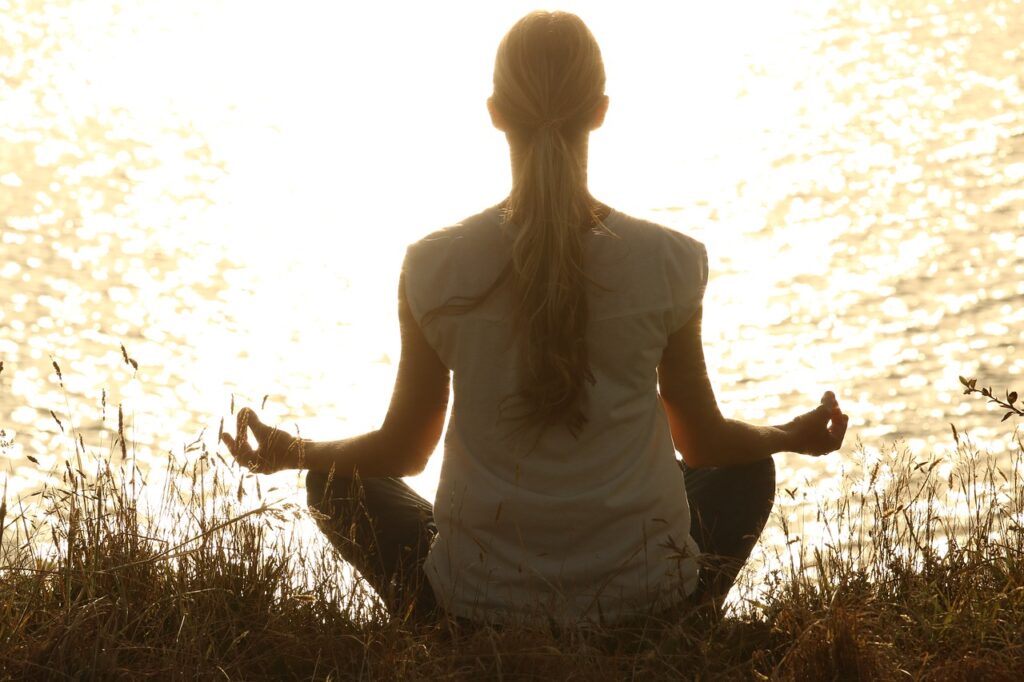 person meditating near lake