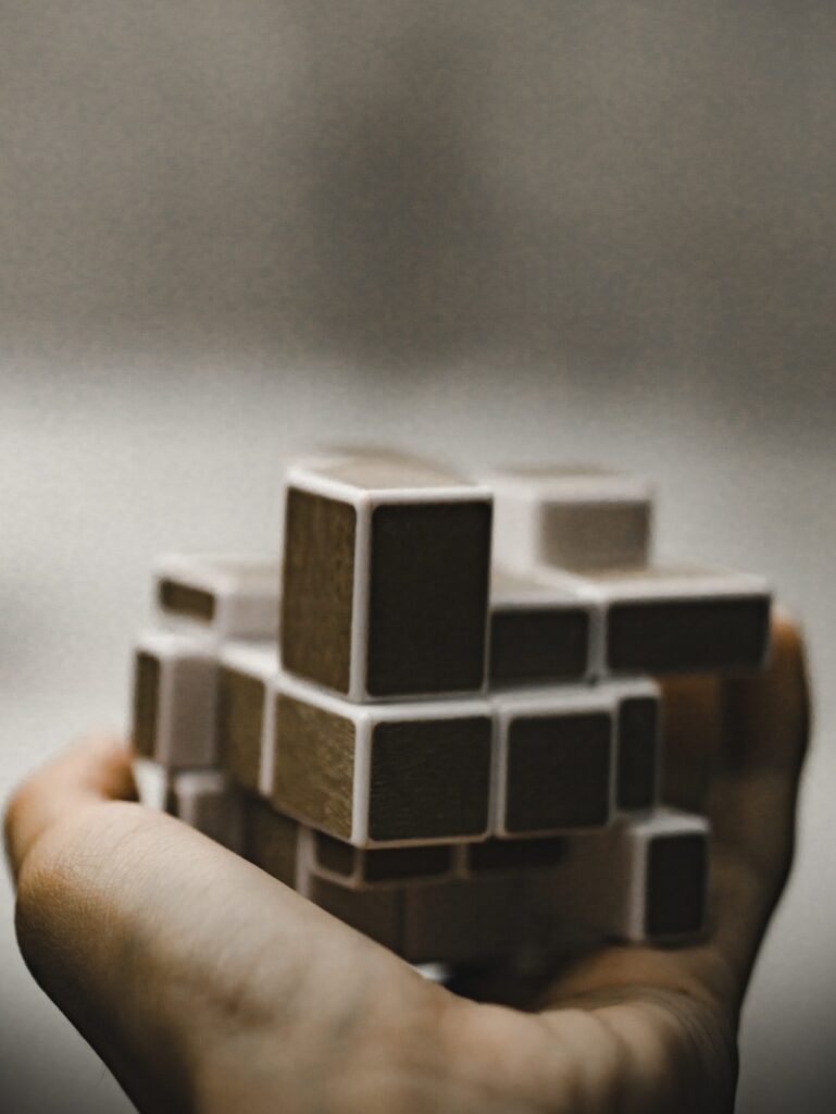 A hand holding a complex-looking wooden puzzle.