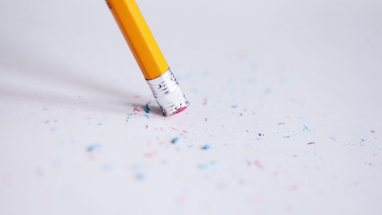 Close-up of a pencil eraser with blue and pink eraser bits on a piece of white paper.