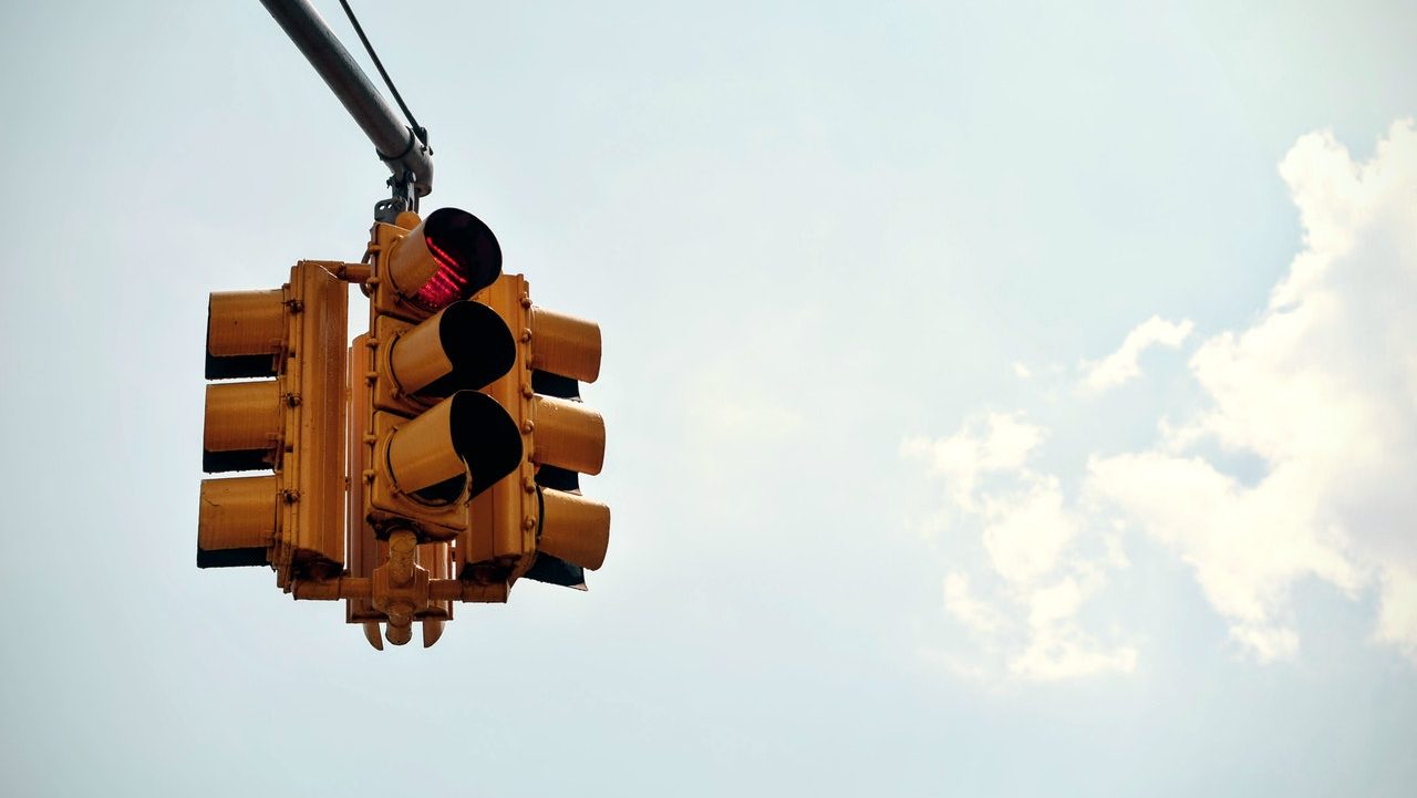 4-way traffic control signal showing red stop light against a bright sky.